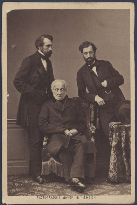 Witoldem i Władysławem, fot. Mayer & Pierson, Paryż, 1860 Starszy mężczyzna o pobrużdżonej twarzy, z siwymi włosami i bokobrodami, siedzący w fotelu, w całej postaci, na wprost, w czarnym surducie i spodniach. Za nim, po obu stronach stoją dwaj brodaci mężczyźni w średnim wieku, w ciemnych ubraniach i białych koszulach z ciemnymi muszkami. Z prawej strony nakryty serwetą stolik, na nim leży cylinder. Fotografia w kolorze sepii.