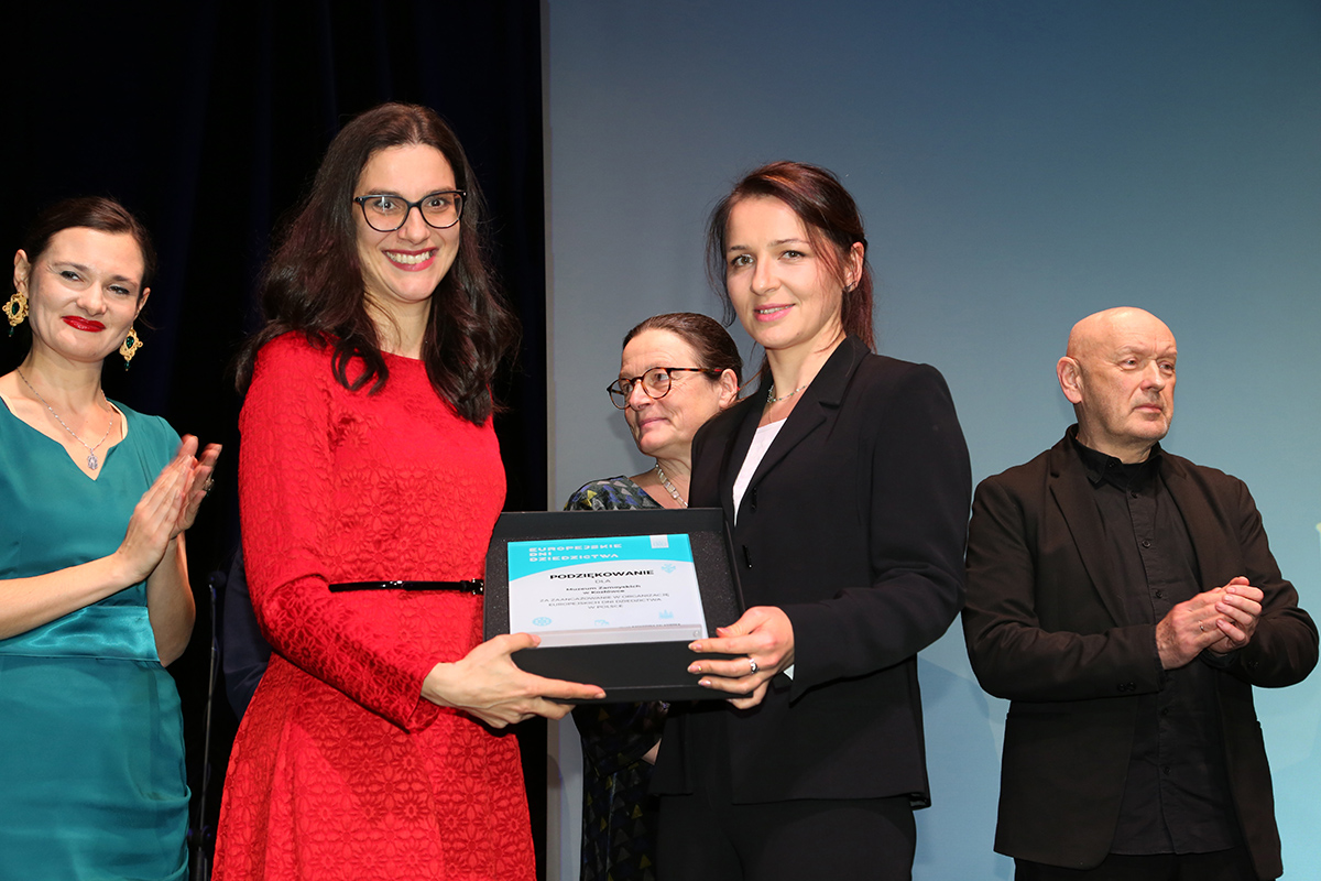 Dr hab. Katarzyna Zalasińska, dyrektor Narodowego Instytutu Dziedzictwa i Katarzyna Kot, kustosz Muzeum Zamoyskich w Kozłówce, 7 grudnia 2022; fot. Paweł Kobek (NID) Fotografia kolorowa przedstawia dr hab. Katarzynę Zalasińską, dyrektor Narodowego Instytutu Dziedzictwa wręczającą pamiątkową plakietę Katarzynie Kot, kustosz Muzeum Zamoyskich w Kozłówce, na pierwszym planie kobiety trzymające pamiątkową plakietę, za nimi dwie inne kobiety i mężczyzna; fot. Paweł Kobek (NID)