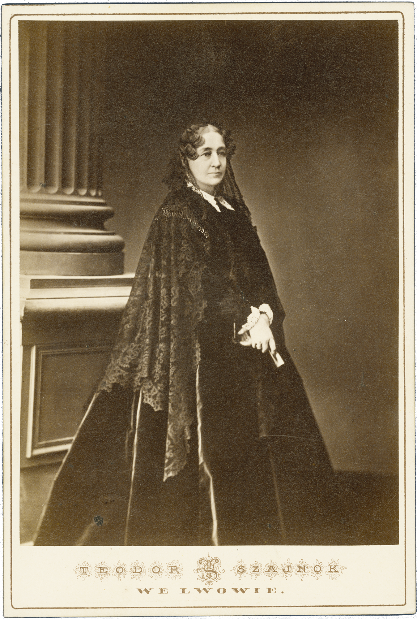 4. Jadwiga z Zamoyskich Sapieżyna, Teodor Szajnok, Lwów, l. 60. XIX w., fotografia zabytkowa, 16,3 x 11 cm, MPK/SW/463 Fotografia archiwalna, czarno biała przedstawiająca dojrzałą kobietę w całej postaci, ubraną w ciemną, długą suknię z czarnym, koronowym welonem na włosach; tło neutralne. Po lewej widoczny fragment kolumny na wysokiej podstawie.