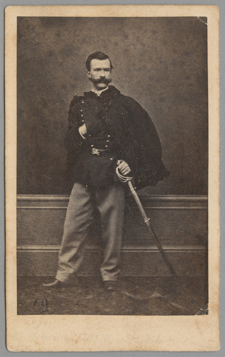 Nepomucen Jan Seyfried, reprod. fot. Wacław Rzewuski, Portret atelierowy Mariana Langiewicza, Poznań, ok. 1863 r., fotografia, nr inw. MHF 1862/II/1-46, zbiory Muzeum Fotografii w Krakowie Fotografia zabytkowa przedstawiająca w pełnej postaci Mariana Langiewicza. Postać ukazana jest na tle ściany z boazerią w jednej trzeciej jej wysokości. Ukazany został młody mężczyzna, zwrócony ciałem lekko w prawo, z głową skręconą w lewo. Włosy ma zaczesane do tyłu i długie podkręcone do góry wąsy. Twarz jest pociągła, wzrok skierowany w lewą stronę. Ubrany jest w mundur z guzikami rozpiętymi na wysokości mostka, pod połę wsuwa prawą dłoń. Na plecy ma zarzucony kożuch z szamerunkiem, na niej widoczny jest pas tkaniny, szarfa upięta od prawego ramienia. U lewego boku dłoń oparta na szabli, ta z kolei ukryta w pochwie sięga podłogi. W pasie ubranie spięte paskiem z klamrą, na której widoczna jest czaszka, poniżej dwie skrzyżowane kości. Spodnie jasne, długie, opadają na buty. Buty skórzane, wypolerowane, błyszczące. Całość w tonacji czarno-białej.
